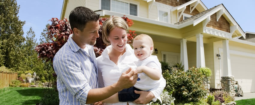 family with baby in front of house